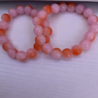 two pink and orange beaded bracelets on a table