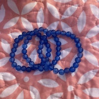 three blue glass beaded bracelets on a pink and white quilt