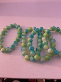 a bunch of green and blue beads on a table