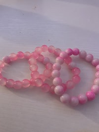 three pink and white beaded bracelets on a table