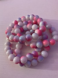 a bunch of pink and purple beads on a white surface