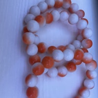 three orange and white beads on a table